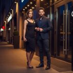 Stylový mladý pár pri vchode do nočného klubu v modernom meste v večernom osvetlení.